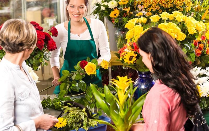 Kuva Shutterstock Kukkakaupassa myyjä ja kaksi asiakasta